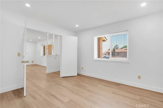 a view of an empty room with a window and wooden floor