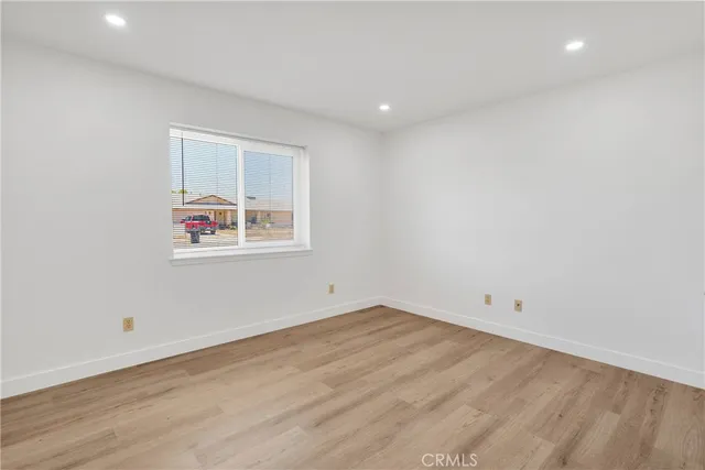 an empty room with wooden floor and window