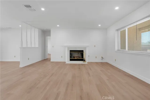 an empty room with wooden floor and fireplace