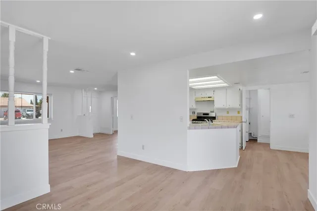 a view of open kitchen with white cabinets and wooden floor