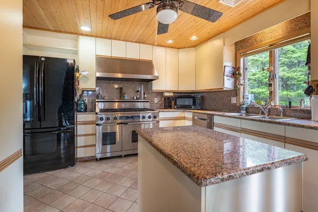 a kitchen with stainless steel appliances kitchen island granite countertop a sink and cabinets