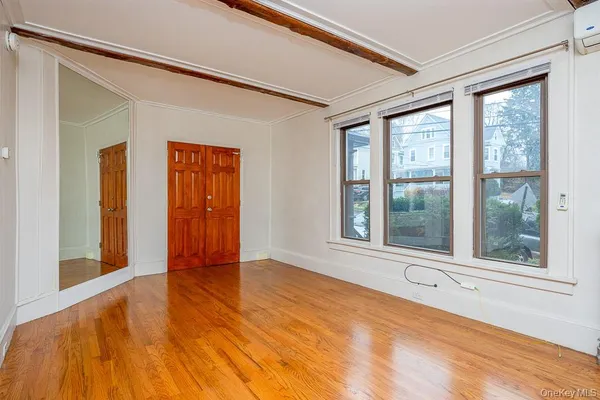 a view of an empty room with a window and wooden floor