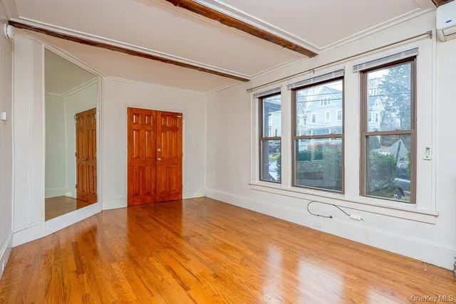 a view of an empty room with a window and wooden floor
