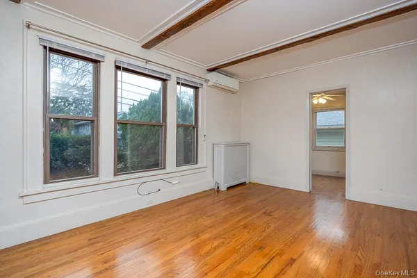 a view of an empty room with a window and wooden floor