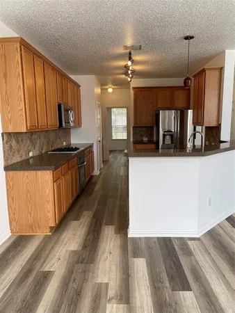 a kitchen with stainless steel appliances granite countertop a refrigerator a stove and a wooden floors