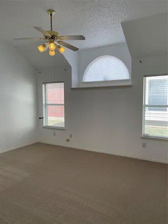 an empty room with a chandelier fan and windows