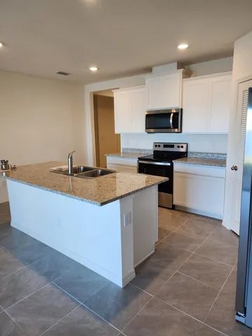 a kitchen with stainless steel appliances granite countertop a sink a stove top oven a counter space and cabinets