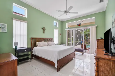 a spacious bedroom with a bed and a flat tv screen on dresser