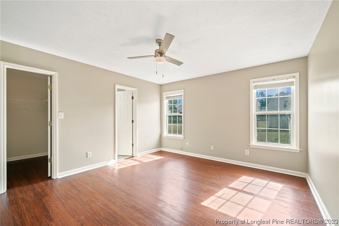 149 Cavalier Drive Raeford, NC 28376 - Photo 15 of 31 an empty room with wooden floor ceiling fan and windows