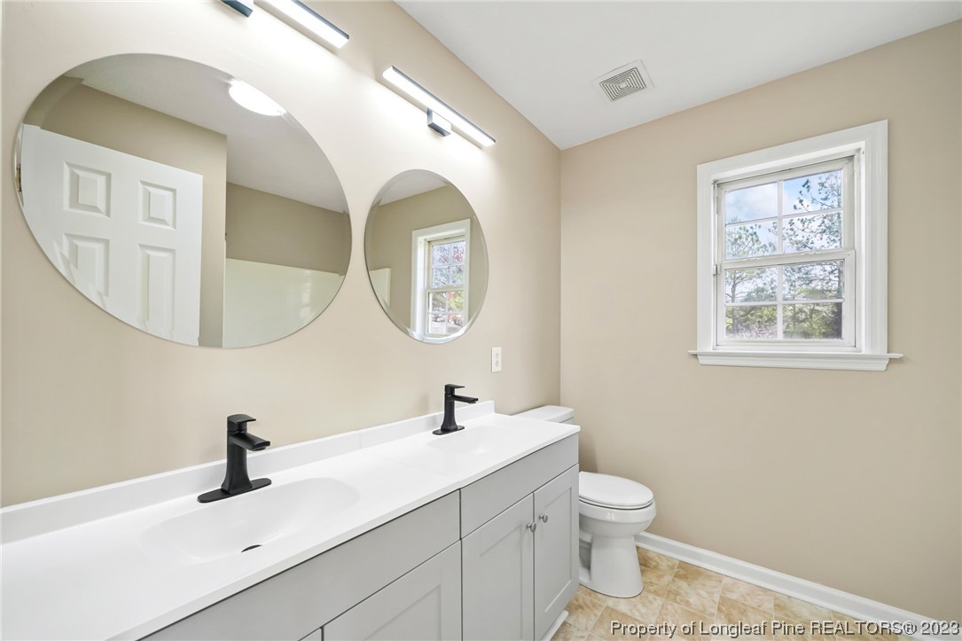149 Cavalier Drive Raeford, NC 28376 - Photo 17 of 31 a bathroom with a toilet a sink and mirror
