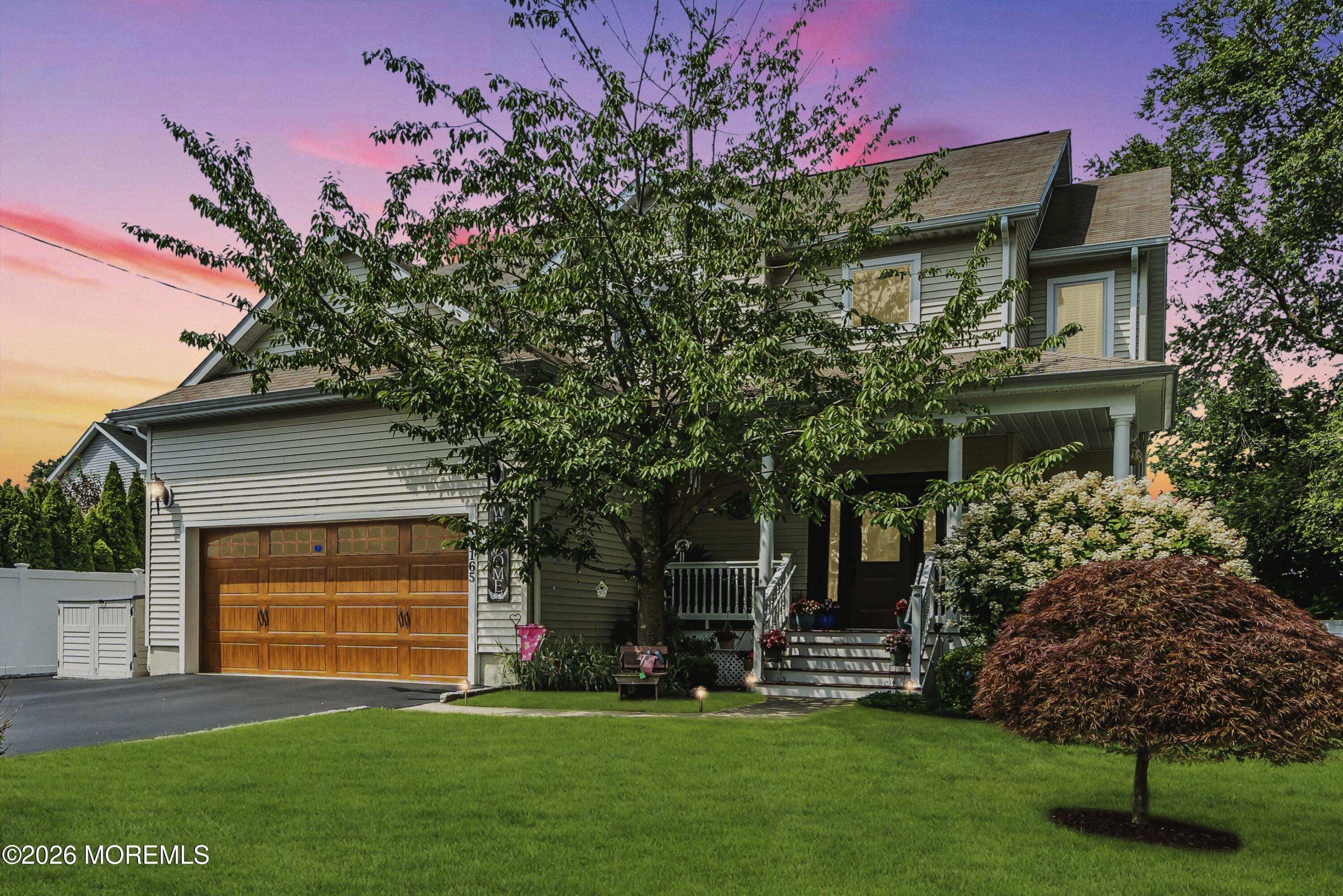 a front view of a house with a garden and trees