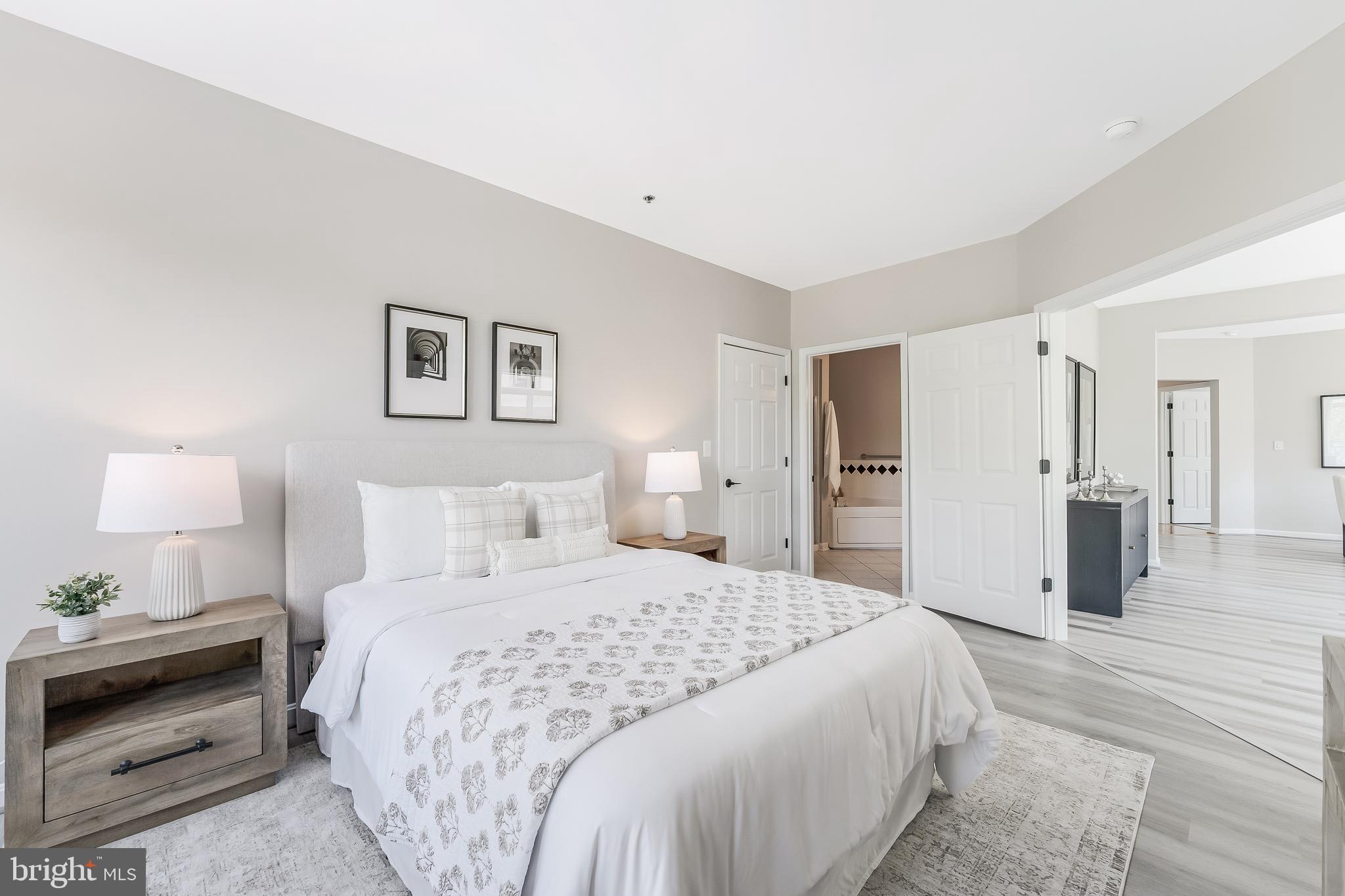 1851 Stratford Park Place, Unit 212 Reston, VA 20190 - Photo 27 of 45 a spacious bedroom with a bed and a lamp