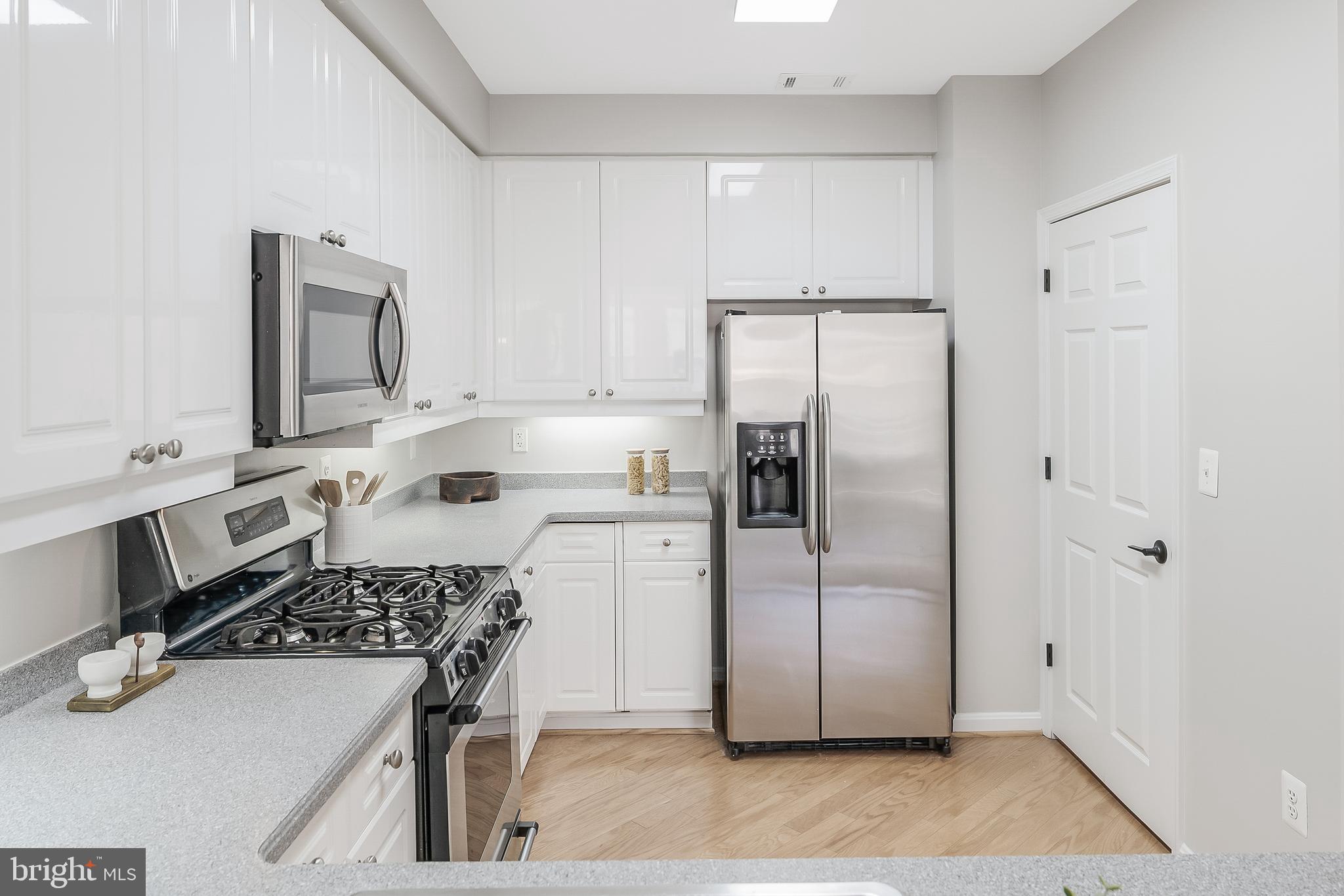 1851 Stratford Park Place, Unit 212 Reston, VA 20190 - Photo 7 of 45 a kitchen with white cabinets and stainless steel appliances