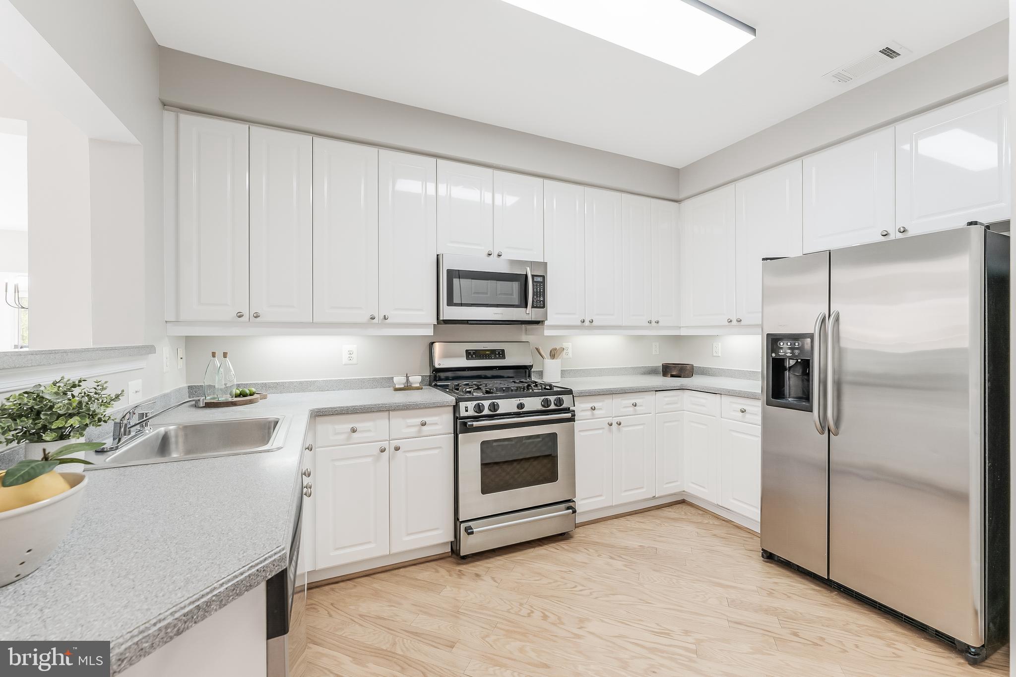 1851 Stratford Park Place, Unit 212 Reston, VA 20190 - Photo 8 of 45 a kitchen with cabinets stainless steel appliances and a potted plant