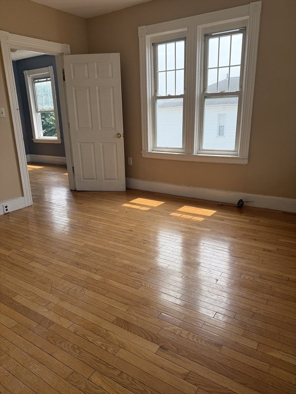 157 Vernon Street, Unit 3 Worcester, MA 01610 - Photo 11 of 15 an empty room with wooden floor and windows