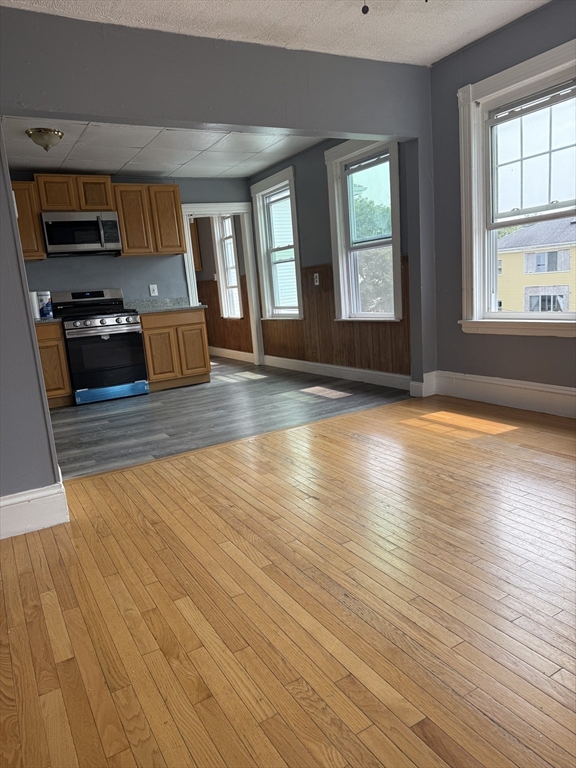 157 Vernon Street, Unit 3 Worcester, MA 01610 - Photo 6 of 15 an empty room with wooden floor and windows