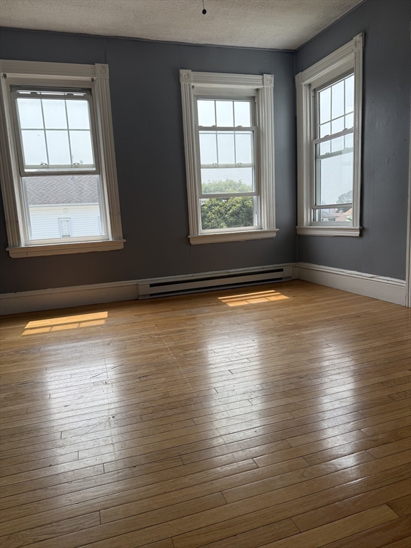 157 Vernon Street, Unit 3 Worcester, MA 01610 - Photo 7 of 15 an empty room with wooden floor and windows