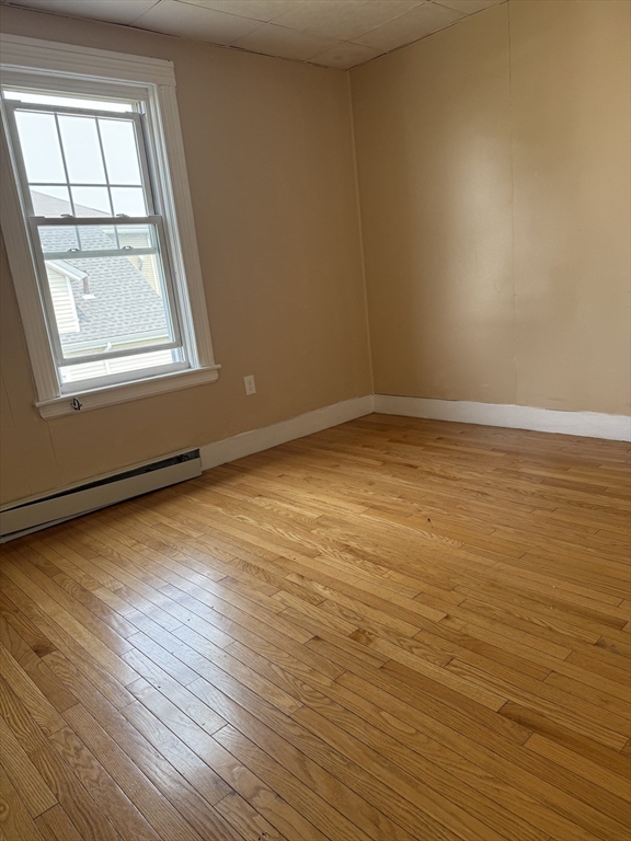 157 Vernon Street, Unit 3 Worcester, MA 01610 - Photo 9 of 15 an empty room with wooden floor and windows