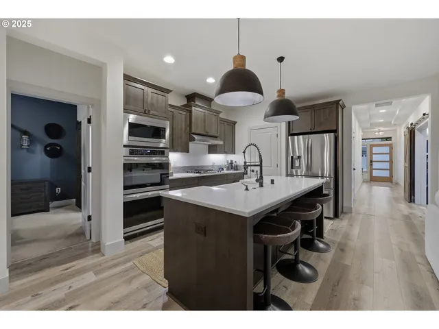 a kitchen with stainless steel appliances a sink a stove a refrigerator and cabinets