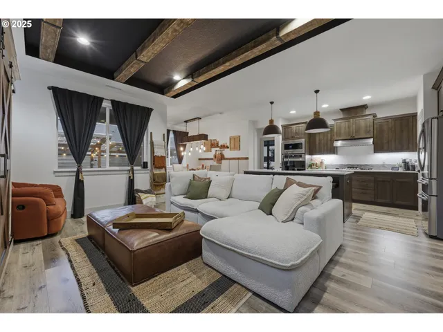 a living room with furniture kitchen view and a large window