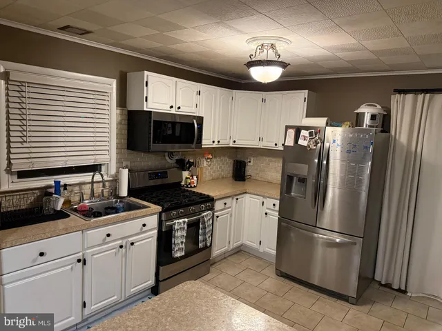 a kitchen with stainless steel appliances granite countertop a refrigerator a stove a sink and a microwave