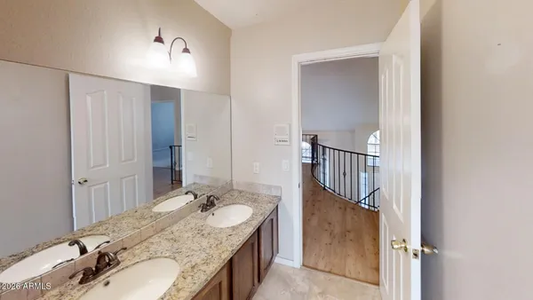 a bathroom with a granite countertop double vanity sink and mirror