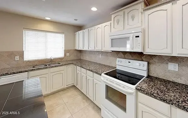 a kitchen with granite countertop white cabinets and white appliances