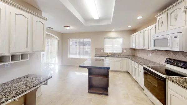 a kitchen with granite countertop white cabinets and stainless steel appliances