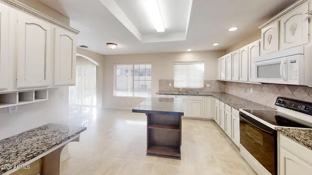 a kitchen with granite countertop white cabinets and stainless steel appliances