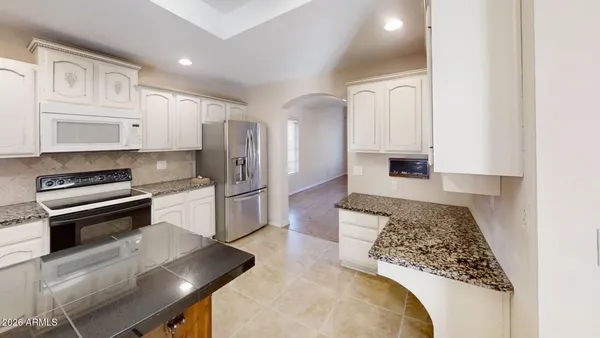 a kitchen with stainless steel appliances granite countertop a refrigerator a stove and white cabinets