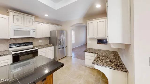 a kitchen with stainless steel appliances granite countertop a refrigerator a stove and white cabinets