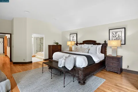 a spacious bedroom with a bed and wooden floor