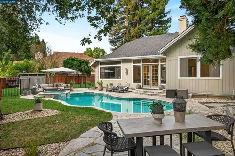 a view of a backyard with swimming pool table and chairs under an umbrella