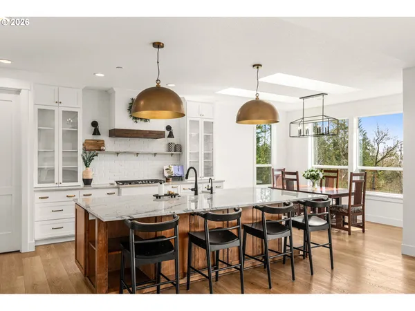 a kitchen with kitchen island granite countertop a dining table chairs and white cabinets