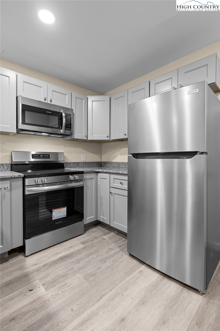 128 Zeb Street, Unit A101 Boone, NC 28607 - Photo 10 of 32 a kitchen with stainless steel appliances white cabinets and wooden floor