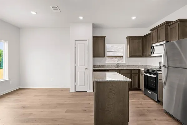 a kitchen with stainless steel appliances granite countertop a refrigerator a sink and a stove