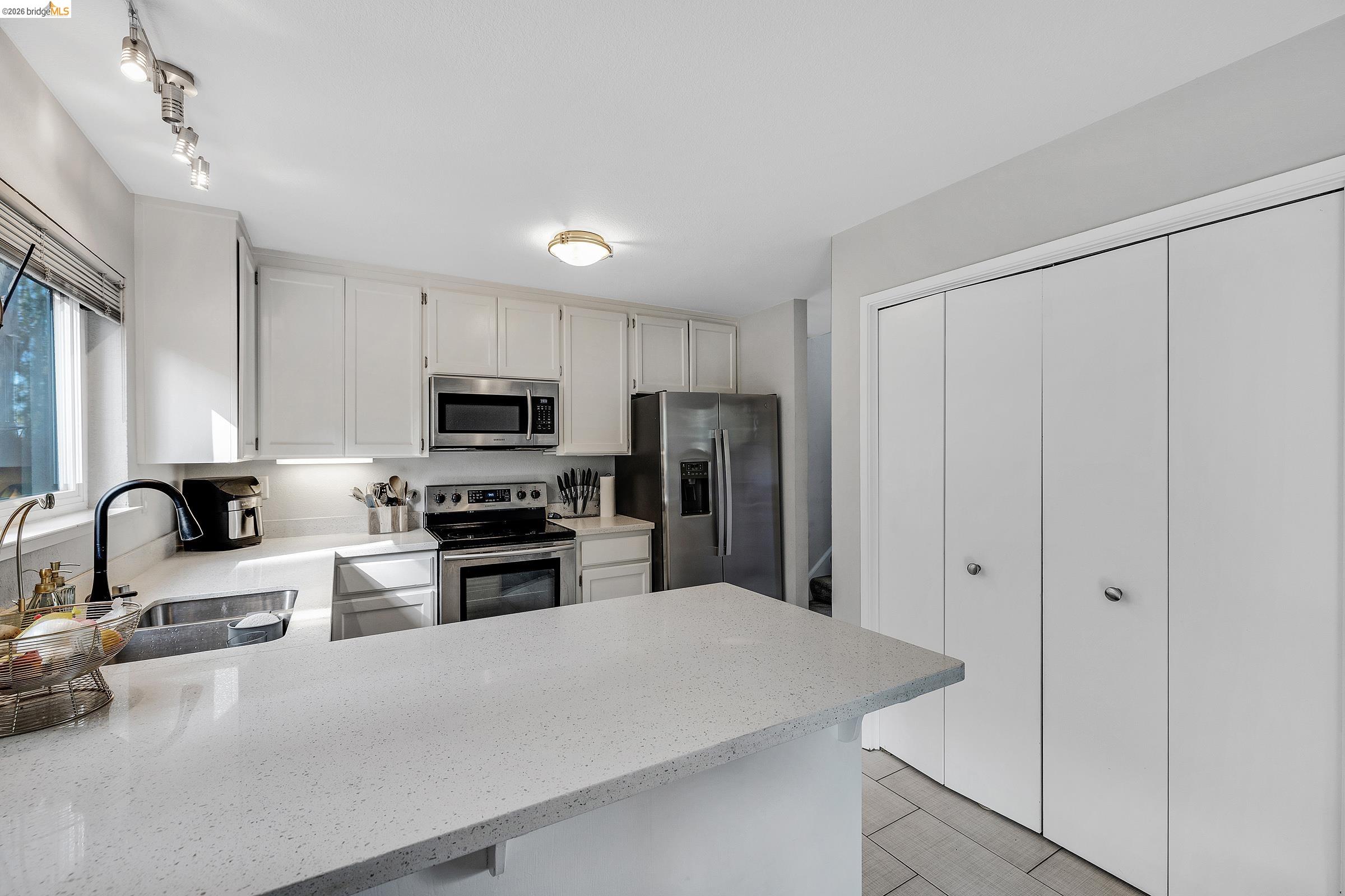407 Vista Heights Road El Cerrito, CA 94530 - Photo 6 of 29 Kitchen featuring stainless steel appliances, white cabinetry, light stone countertops, and a peninsula