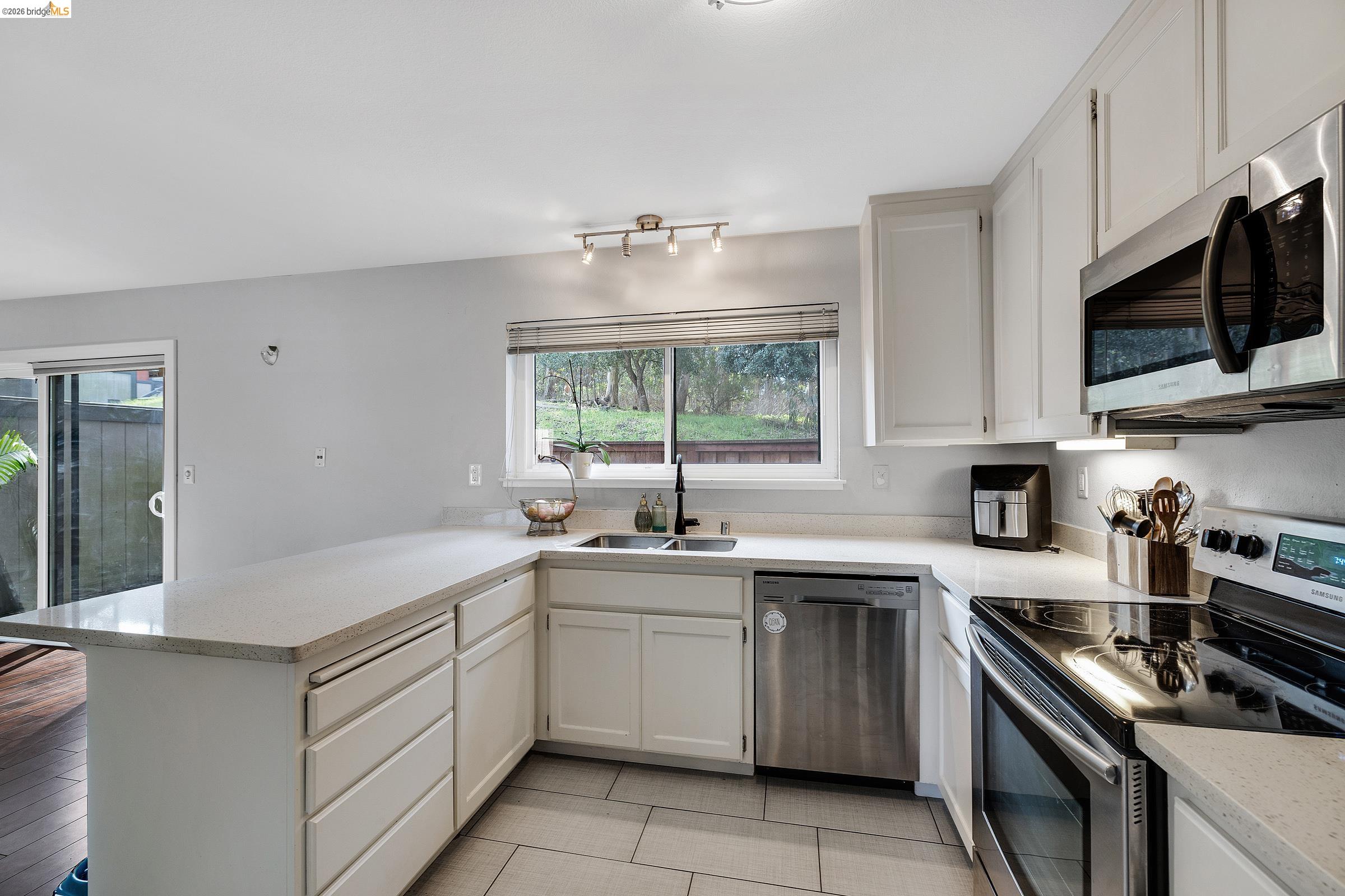 407 Vista Heights Road El Cerrito, CA 94530 - Photo 7 of 29 Kitchen with stainless steel appliances, white cabinets, a peninsula, and light stone counters