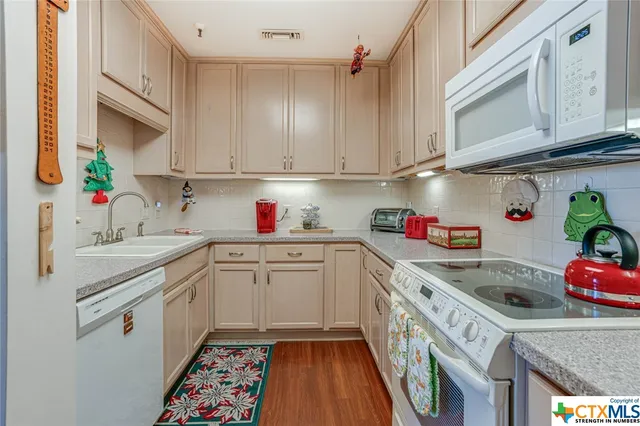 a kitchen with granite countertop a sink stainless steel appliances cabinets and utility