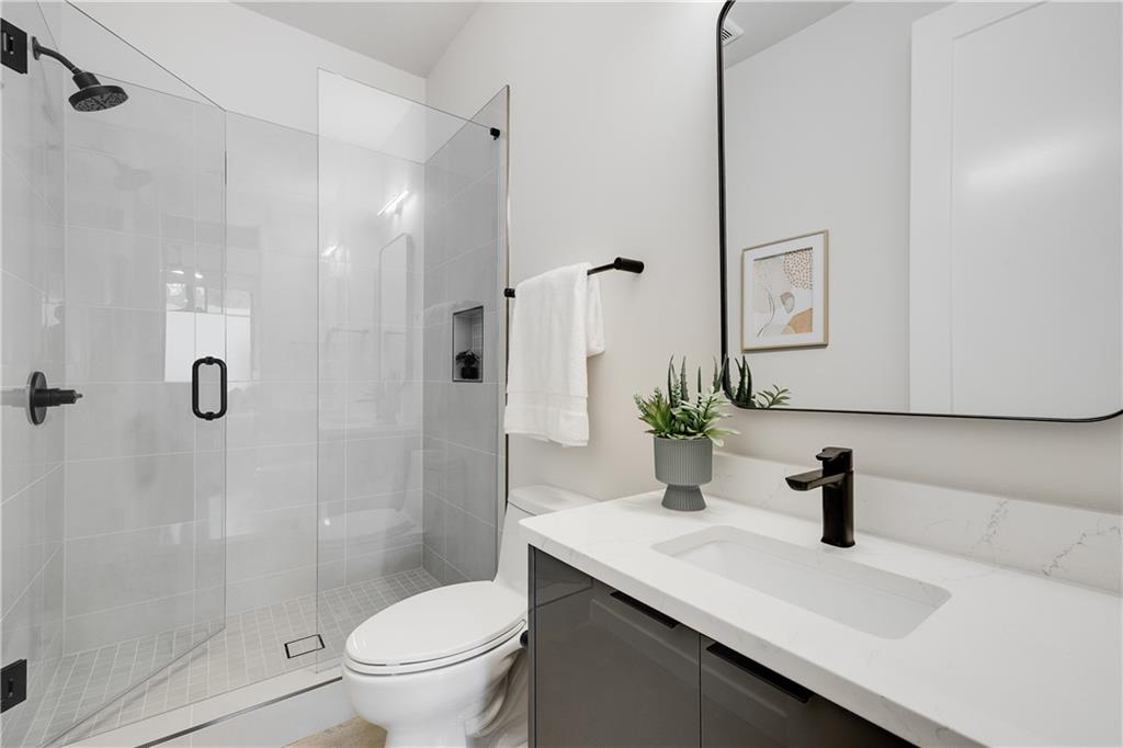 105 Georgia Avenue Southeast, Unit 1 Atlanta, GA 30312 - Photo 22 of 40 a bathroom with a sink a toilet a glass door a shower and vanity