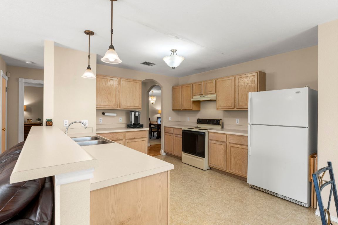 141 Sydney's Way Buda, TX 78610 - Photo 12 of 37 a kitchen with kitchen island a stove a sink a refrigerator and white cabinets with wooden floor