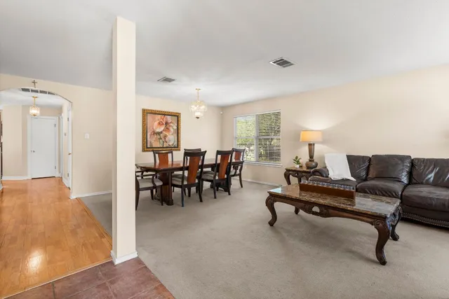a living room with furniture and a dining table with wooden floor