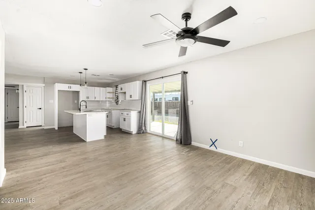 a view of a kitchen with a sink cabinet a ceiling fan and wooden floor