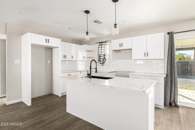 a kitchen with stainless steel appliances granite countertop a sink a stove a refrigerator and island with wooden floor