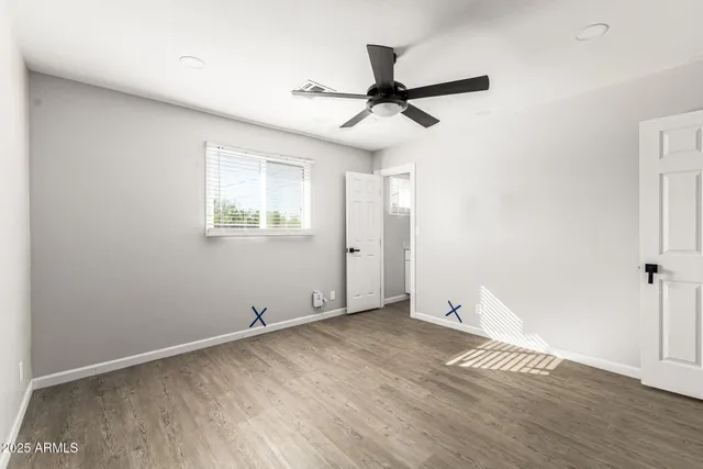 an empty room with wooden floor fan and windows