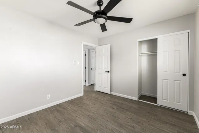 an empty room with wooden floor and a ceiling fan