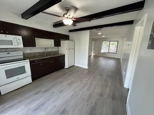 a large kitchen with stainless steel appliances granite countertop a stove top oven a sink dishwasher a dining table and chairs with wooden floor