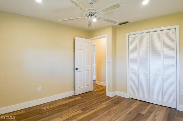 an empty room with wooden floor and a ceiling fan