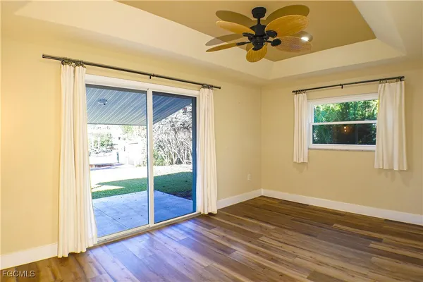a view of an empty room with a window and wooden floor