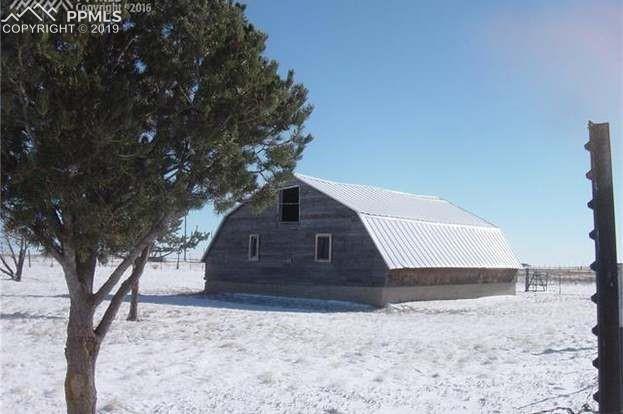 13495 South Lauppe Road Yoder, CO 80864 - Photo 7 of 12 The back side of the barn with several mature pinon trees.